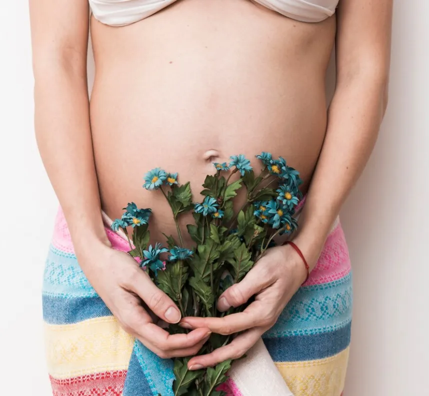 Mujer embarazada sosteniendo un ramo de flores