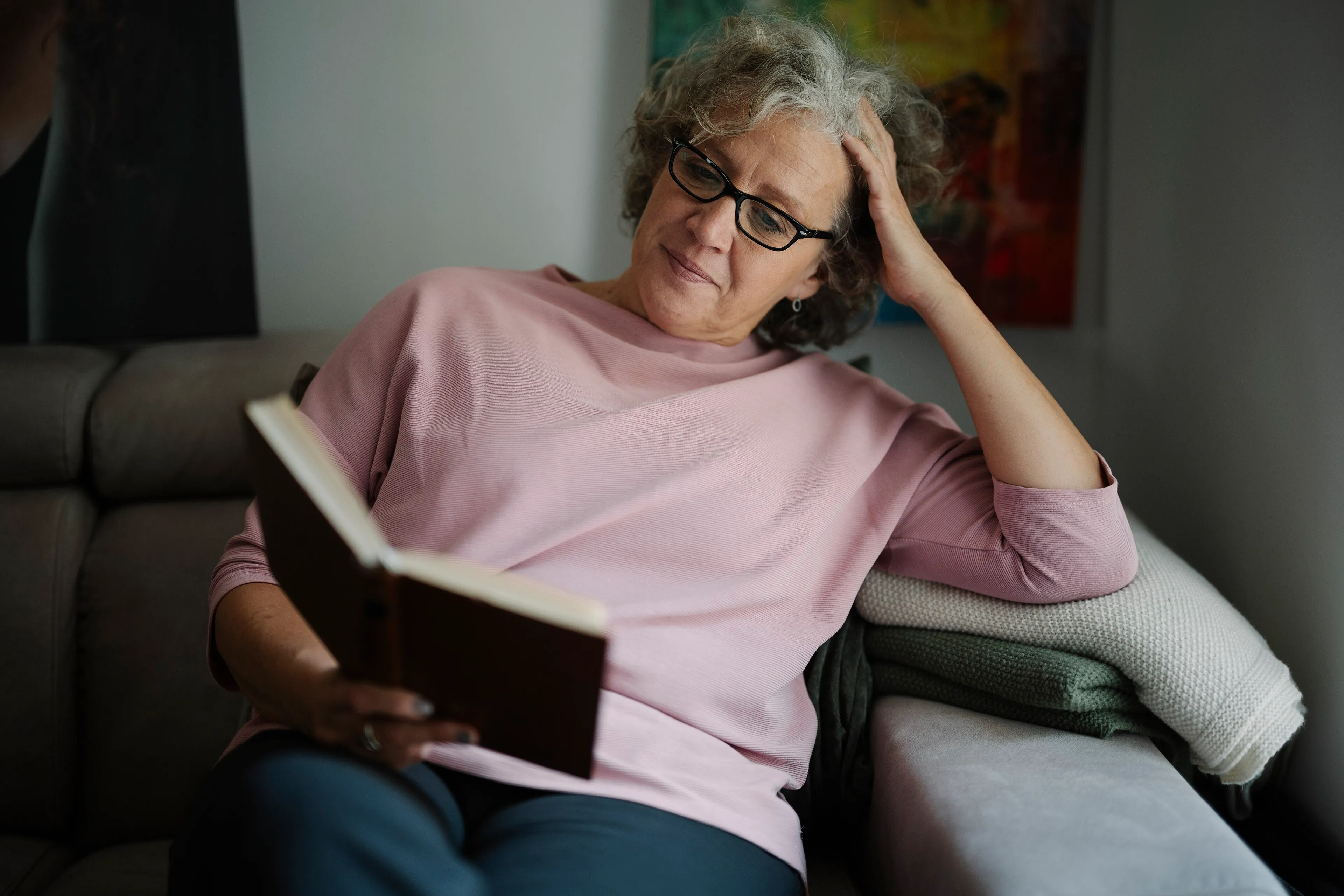 Mujer madura leyendo un libro en el sofá de su salón